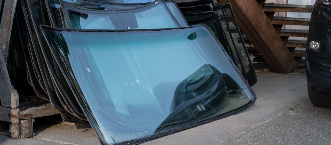 Heaps of used demolished windshield front car glass. Car service insurance. Automobile waste.