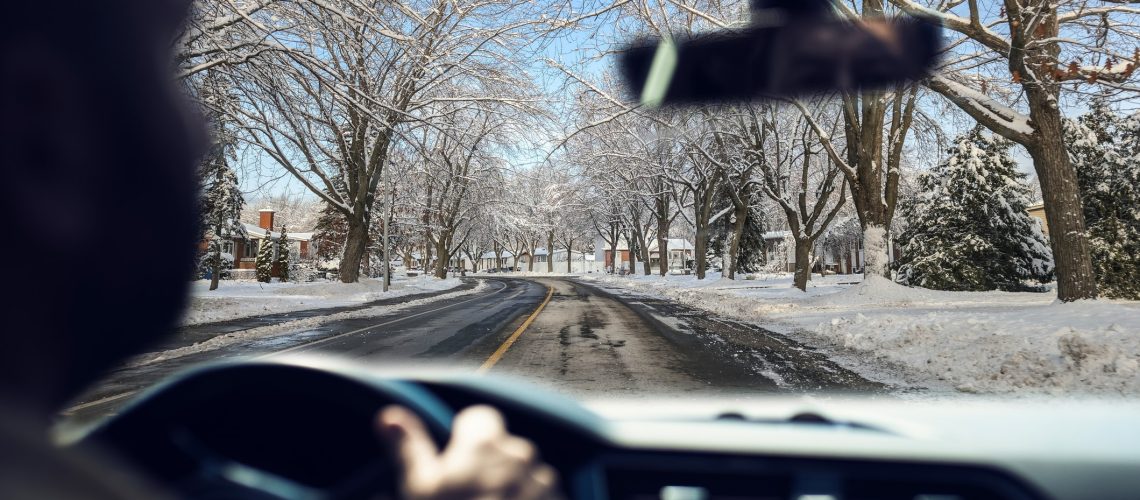 Driving on winter conditions. View from inside the car. The road and the trees are covered in snow.